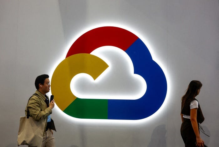 People walk past a colorful Google Cloud logo.