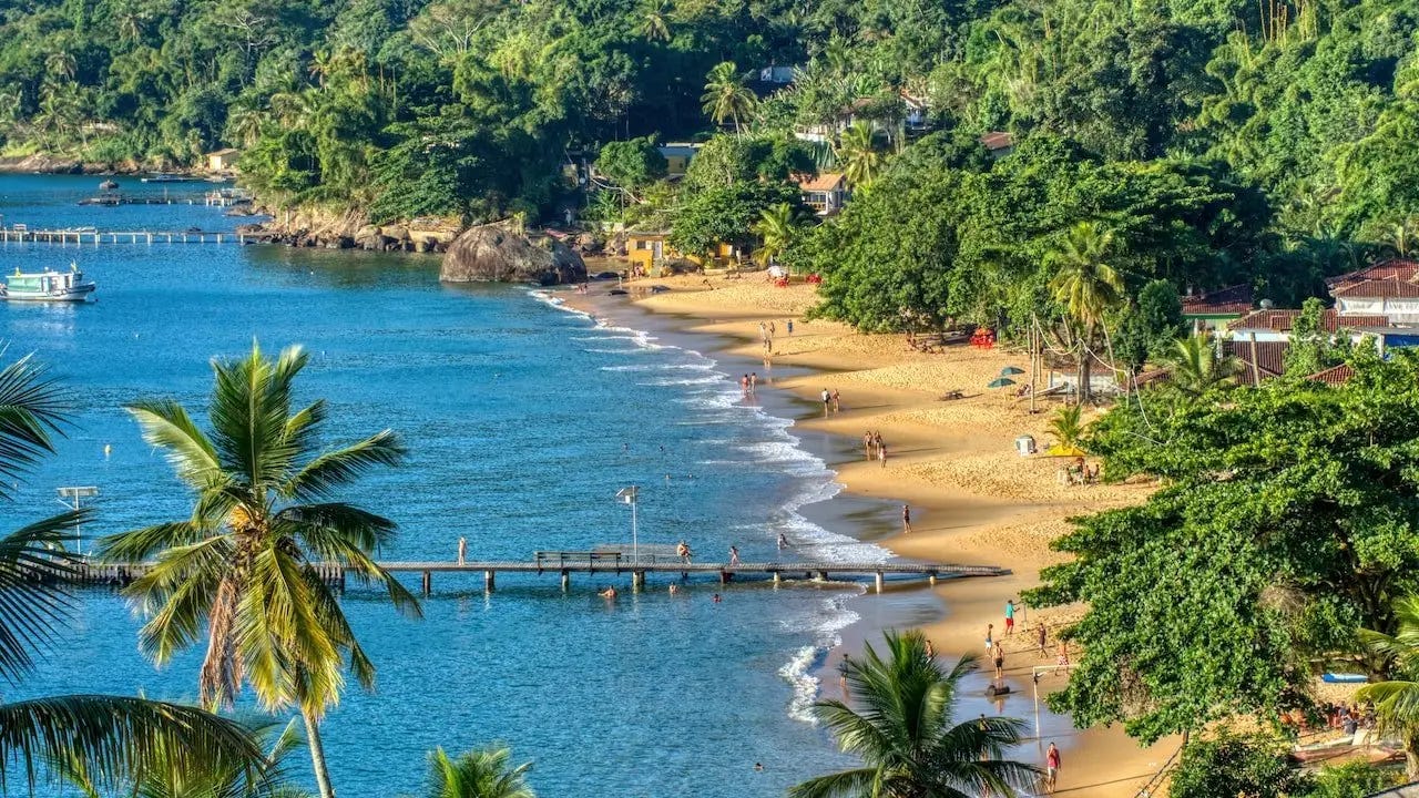 View of golden beach between jungle and turquoise sea from above