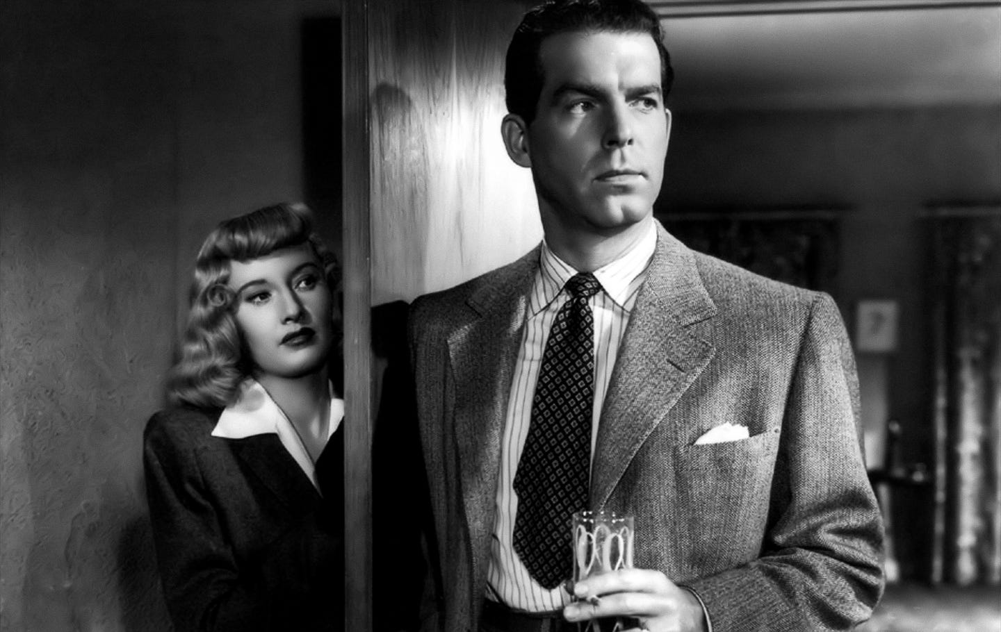 Barbara Stanwyck peers out from behind a doorframe with cold calculation, while Fred MacMurray stands in the foreground in a sharp suit, holding a drink and cigarette—both caught in a noir standoff thick with tension and deception. Barbara Stanwyck peers out from behind a doorframe with cold calculation, while Fred MacMurray stands in the foreground in a sharp suit, holding a drink and cigarette—both caught in a noir standoff thick with tension and deception.