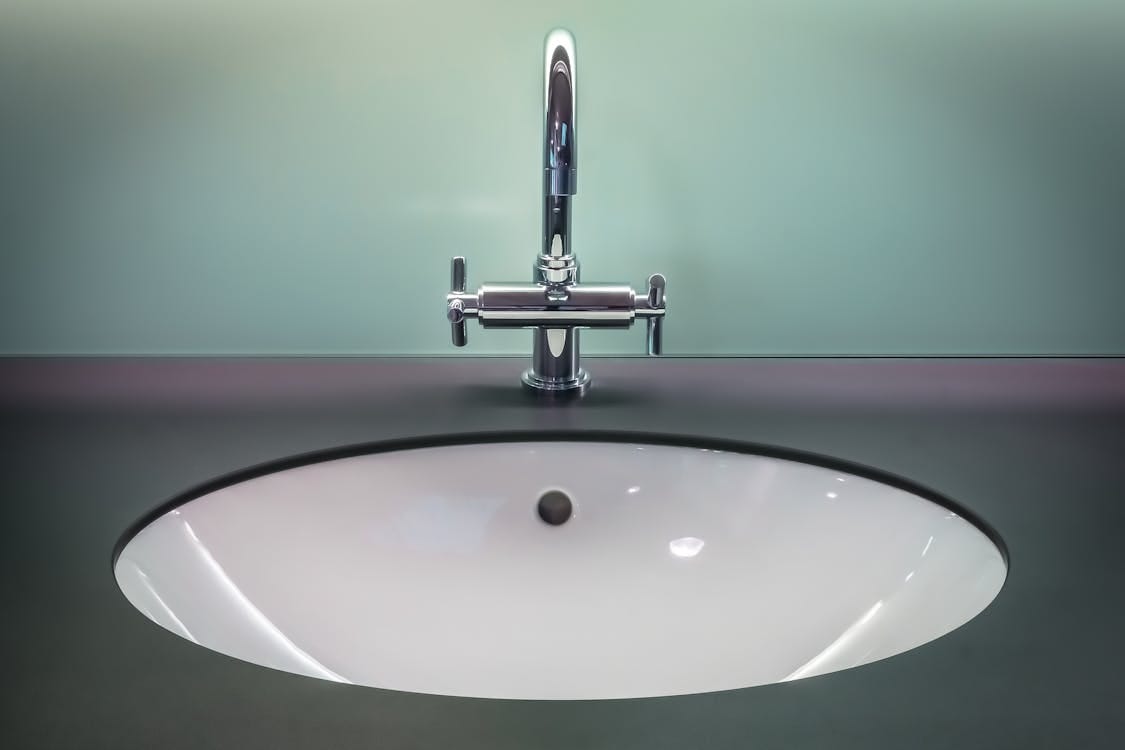 Free A sleek modern bathroom sink with a shiny stainless steel faucet on a dark vanity. Stock Photo