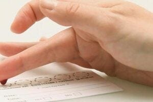 Hand leaving a drop of blood on a medical test card