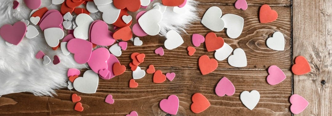 heart-shaped assorted-color cutout decors place on wooden surface