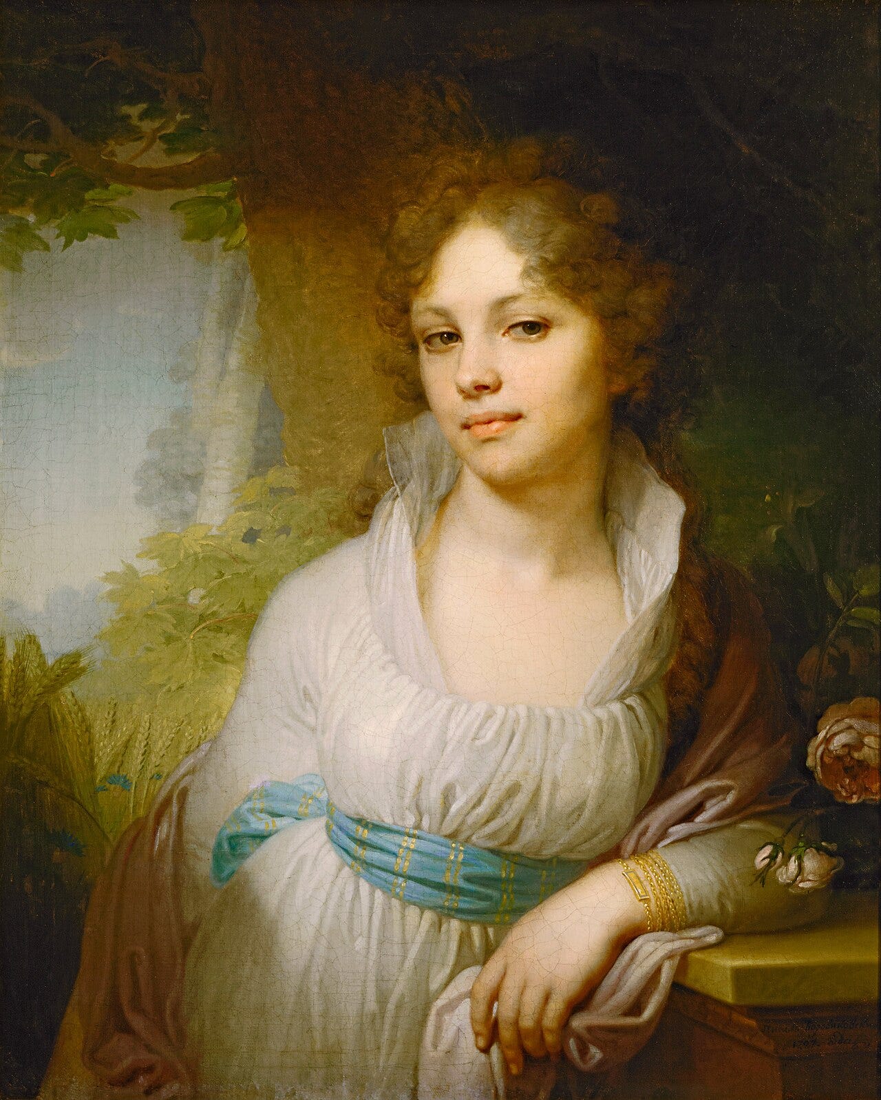 Portrait of a young woman with curly hair in a white dress and a blue sash, leaning on a stone ledge in a garden