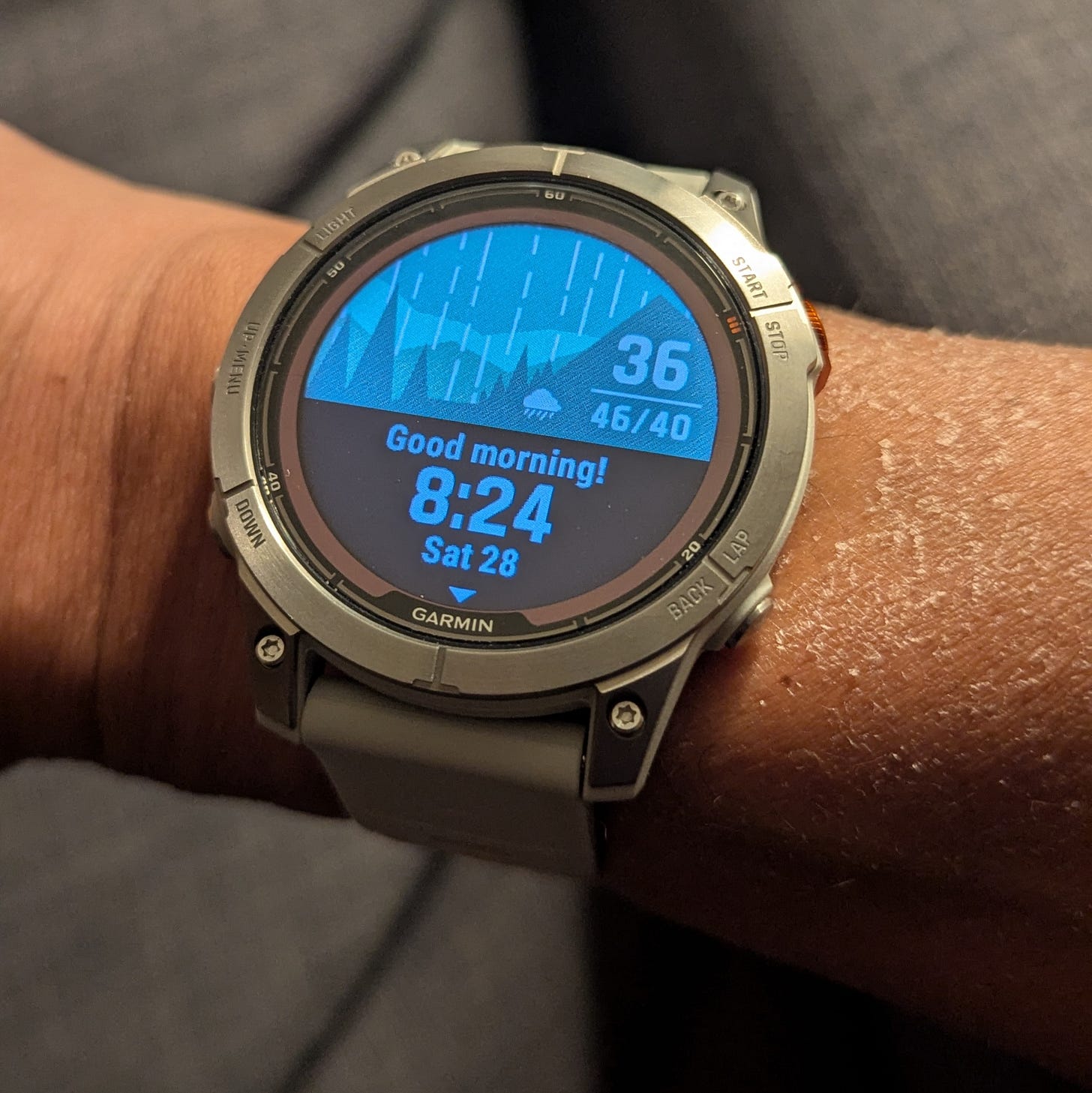 Garmin smart watch being worn. Screen says "Good morning / 8:24 / Sat 28"