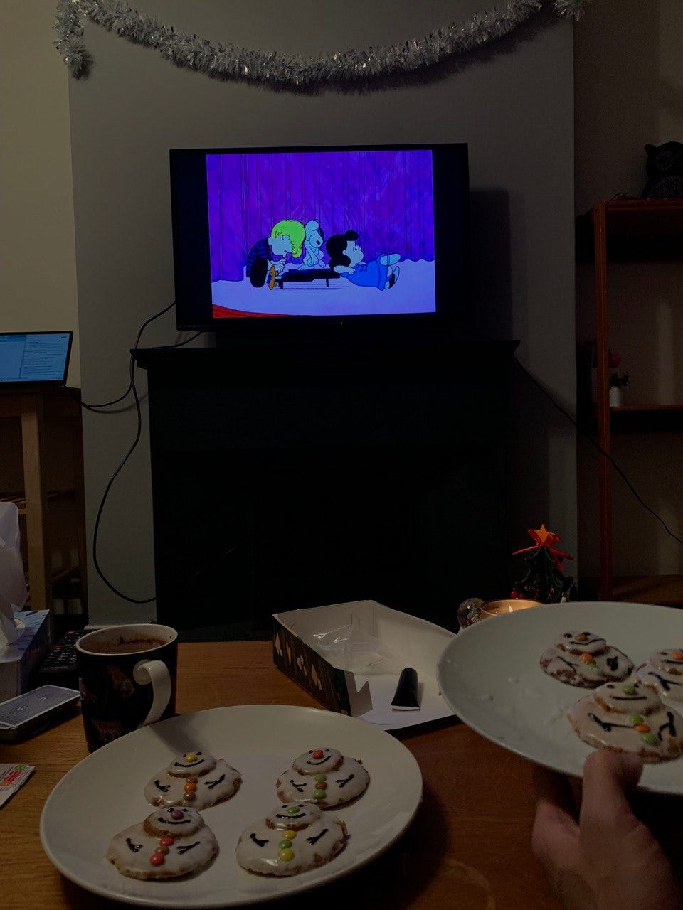 A photo of snowman Christmas cookies, with the movie 'A Charlie Brown Christmas' playing in the background