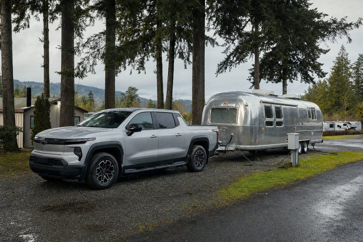 Silver Silverado EV and tandem-axle Airstream at an Oregon KOA-style campsite with an RV electrical pedestal. Silver Silverado EV and tandem-axle Airstream at an Oregon KOA-style campsite with an RV electrical pedestal.