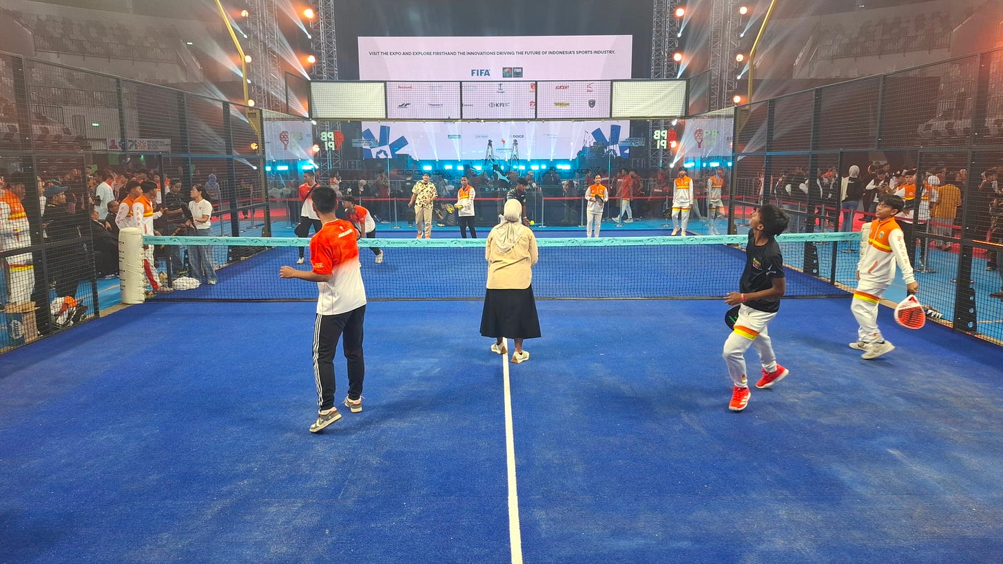Several people play padel together on a fenced indoor court with a standing audience watching during the 2025 Indonesia Sports Summit at the Indonesia Arena in Jakarta.