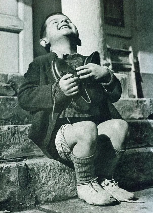 Black and white photograph from 1946 of Werfel, a six-year-old Austrian orphan, beaming with joy as he clutches a new pair of shoes to his chest. Black and white photograph from 1946 of Werfel, a six-year-old Austrian orphan, beaming with joy as he clutches a new pair of shoes to his chest.