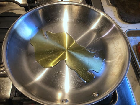 A gallery of five images of the cooking process 1: Oil heating in a pan 2: The sausages being mashed with a potato masher. 3: The cooked sausage on a sheet pan 4: Garlic being added to the pan, which already contains the rapini 5: Three corks jammed under the hande of the pan's lid, creating a handle that's cool to the touch.. 