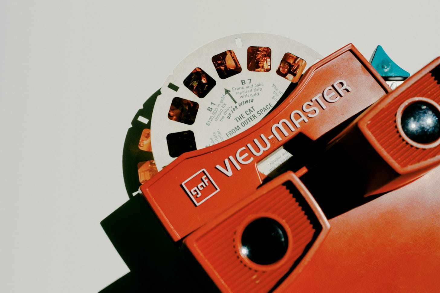 Photo of a red plastic view-master for looking at small photographic slides on a cardboard wheel. Photo of a red plastic view-master for looking at small photographic slides on a cardboard wheel.