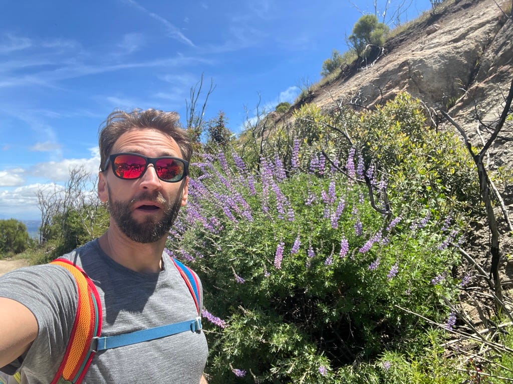 A person taking a selfie in front of a rocky hill

Description automatically generated with medium confidence