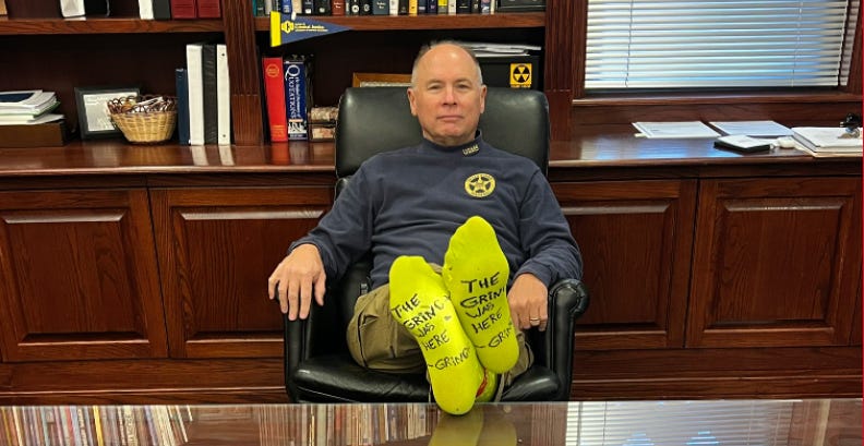 A man wearing yellow socks is sitting in an office chair at a desk. A man wearing yellow socks is sitting in an office chair at a desk.