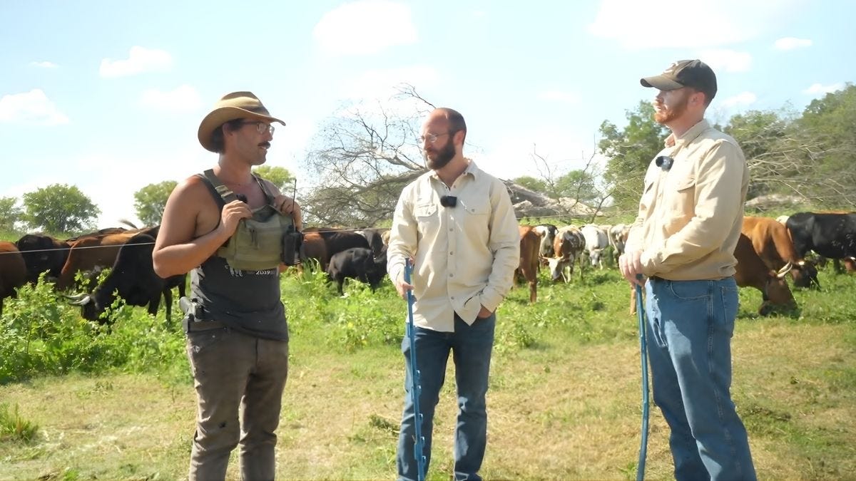 Three men stand in front of a grazing herd at Smoke River Ranch in Oklahoma, discussing ultra-high-density grazing and regenerative cattle management.