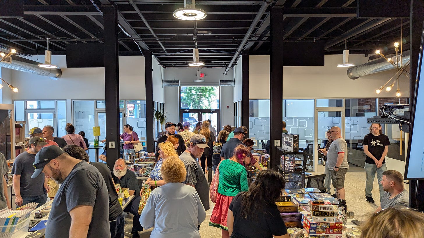 vendors and attendees in large room with many tables filled with board games. vendors and attendees in large room with many tables filled with board games.