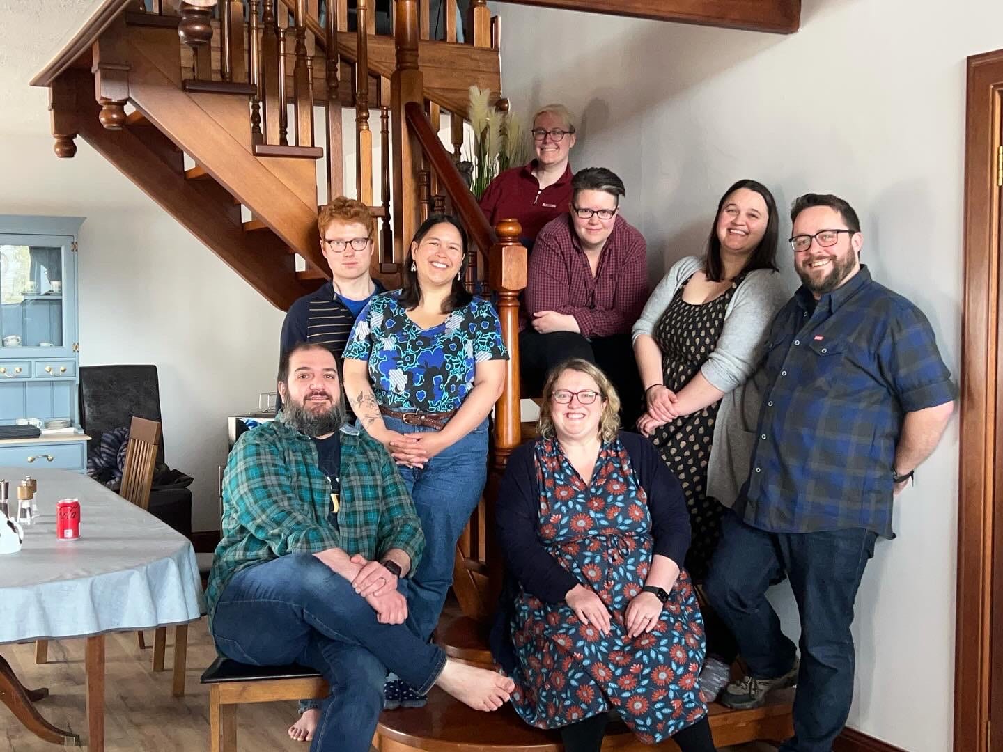 A picture of some lovely smiling authors gathered on the stairs in a swiss family portrait style. Names in caption below.