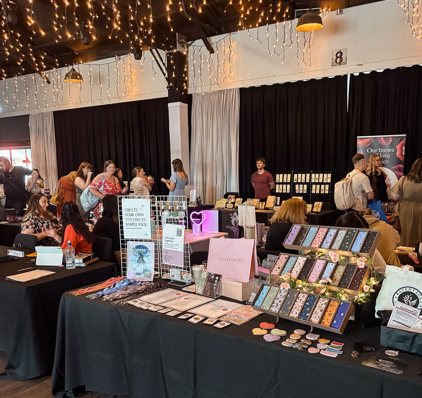 An array of vendors on tables with black table cloths. They are showing their book related wears. An array of vendors on tables with black table cloths. They are showing their book related wears.