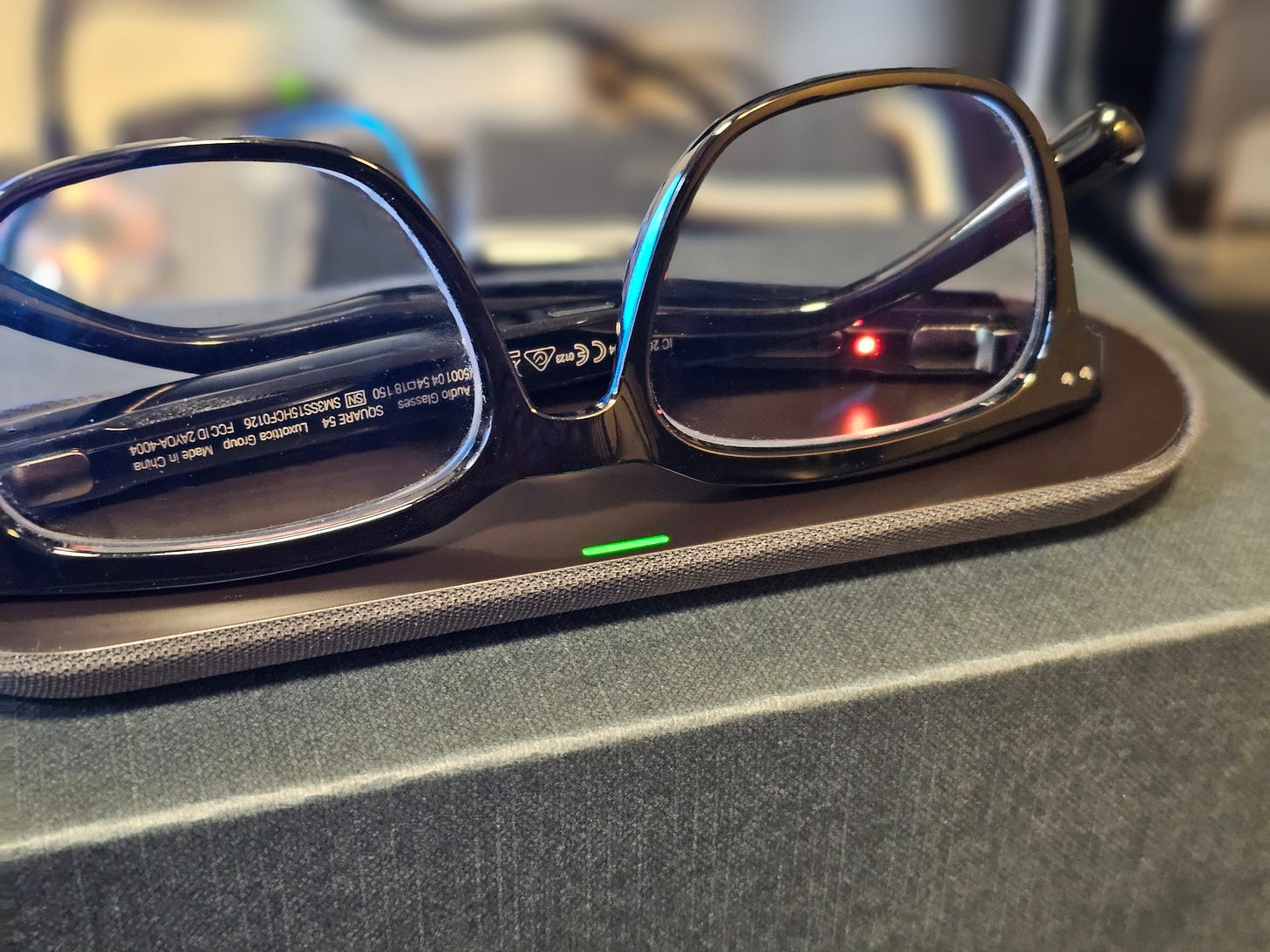 Nuance Audio Hearing Glasses sitting on their magnetic charging pad.