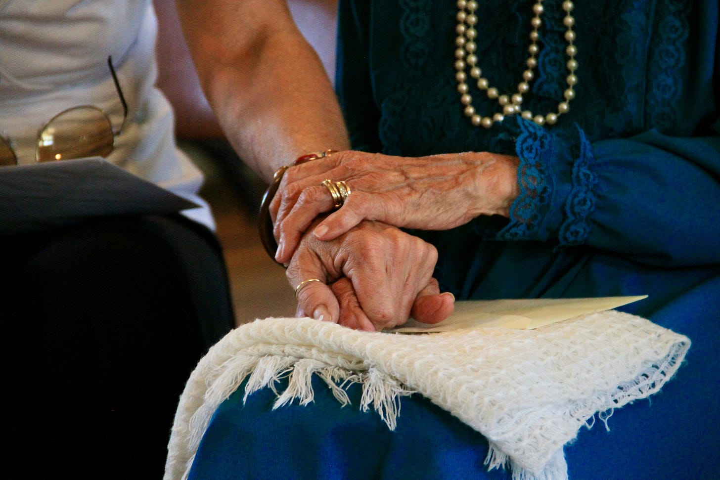 An elderly person's hand holds that of someone younger.