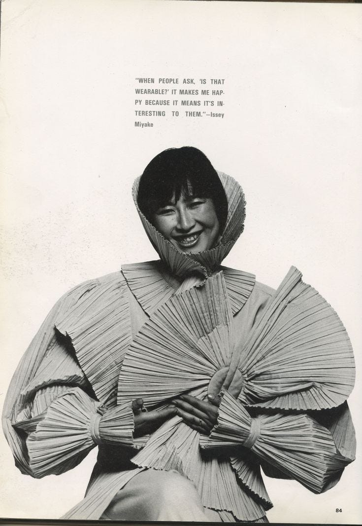 This may contain: an old photo of a woman with her hands on her hips, wearing a hood and pleated dress