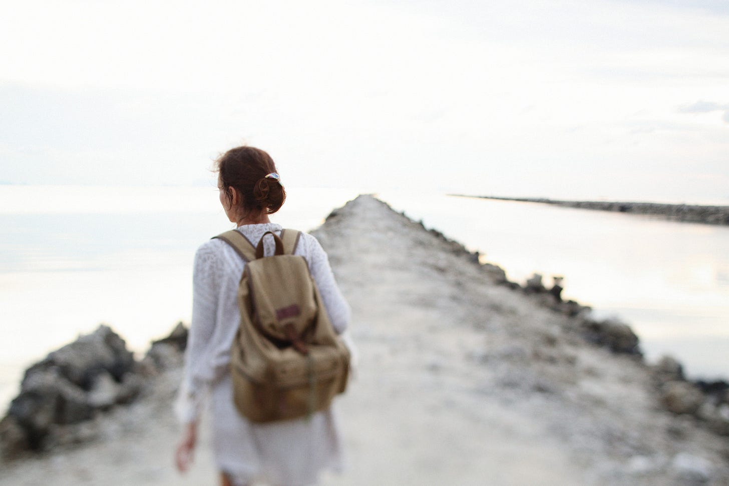 A woman walking alone on a coastal path during a tranquil summer evening