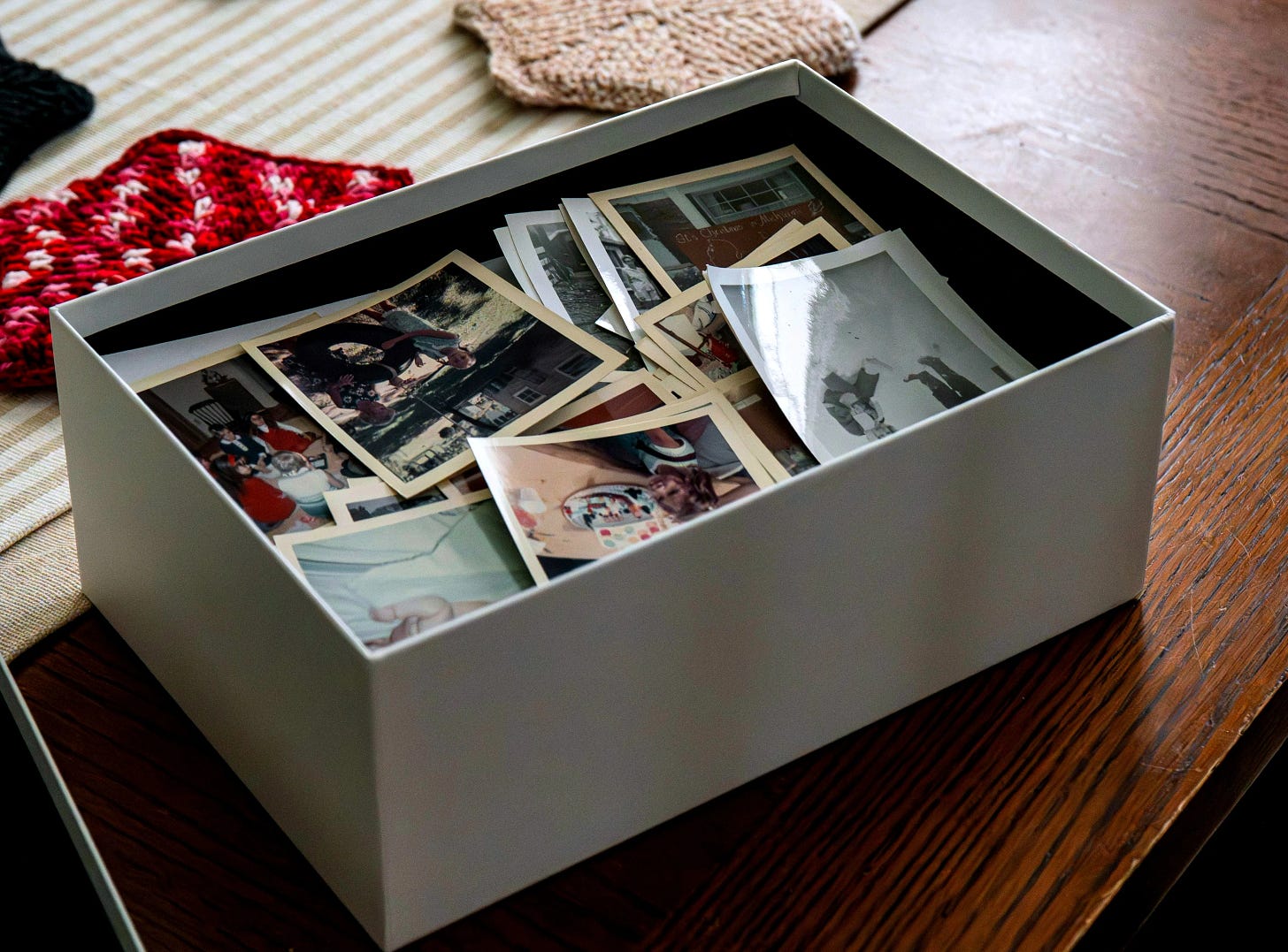 Box of printed Mexican American family photos on a wooden table.