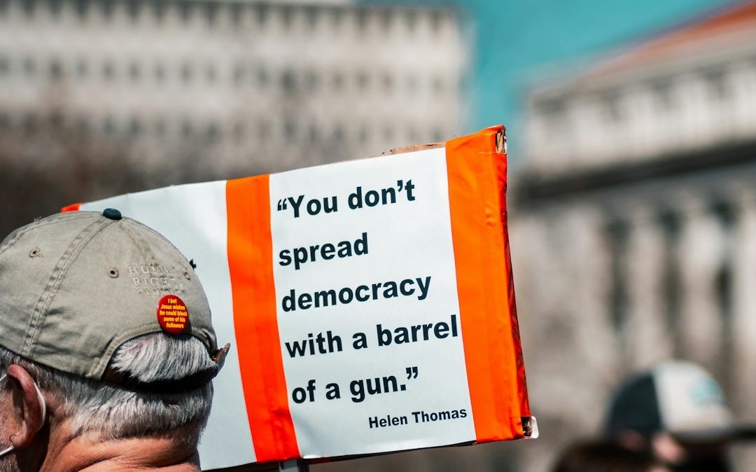 man in black jacket holding white and orange signage during daytime