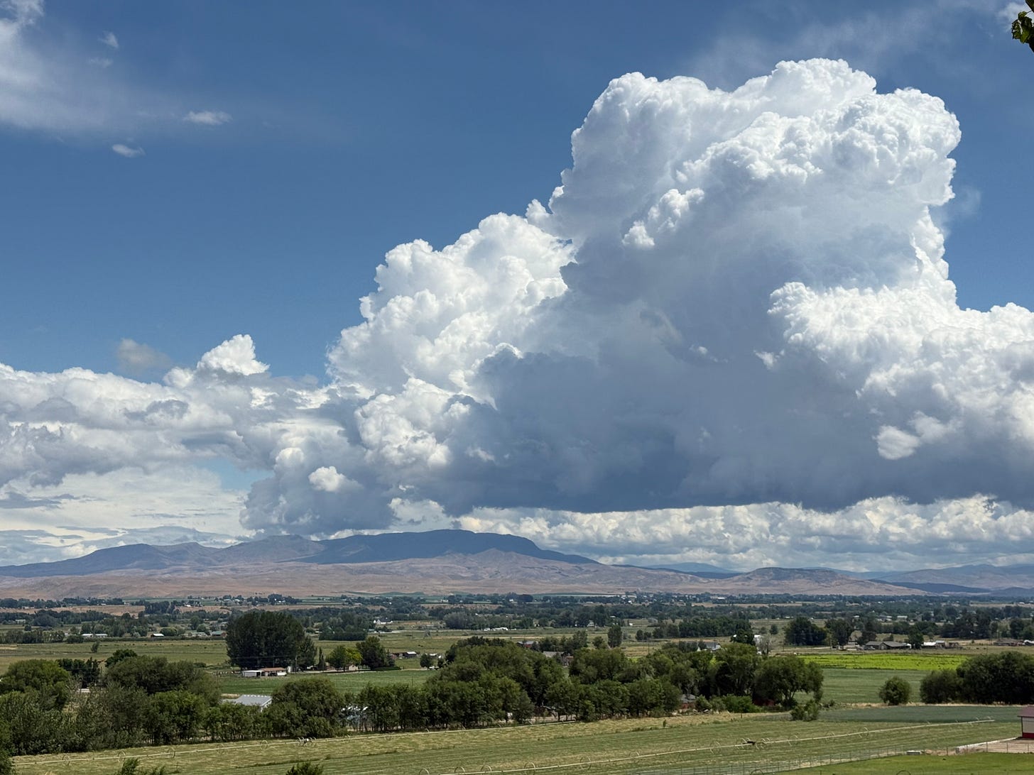 A huge thundercloud over the Butte with blue skies behind it.
