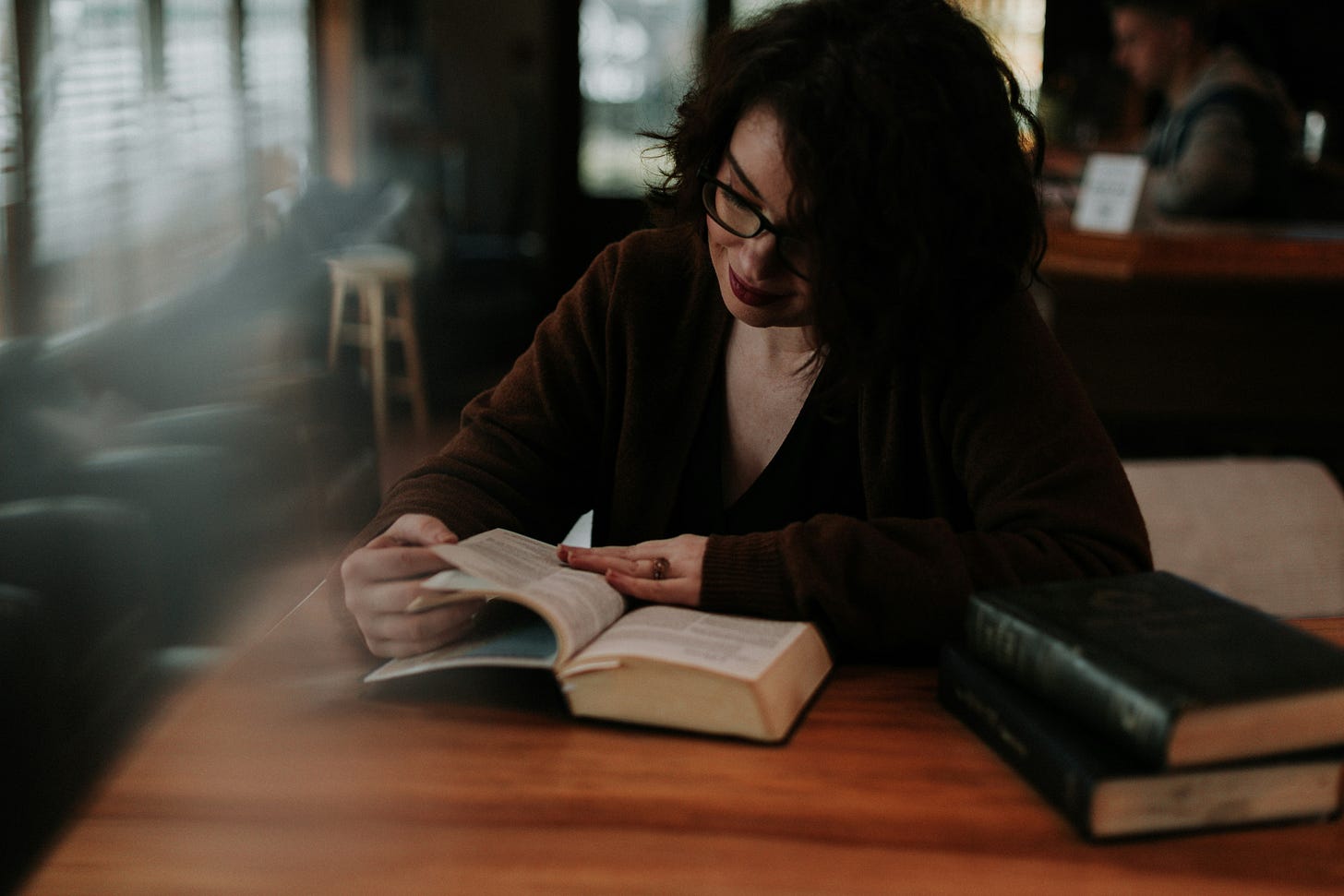 woman with brown hair smiling and reading a book woman with brown hair smiling and reading a book