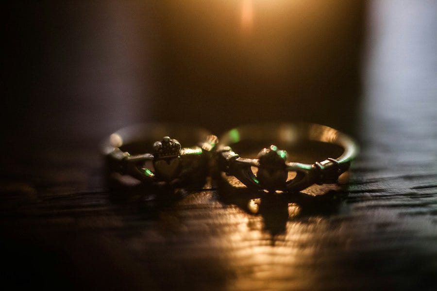 A gold Claddagh ring, backlit on a wooden table.