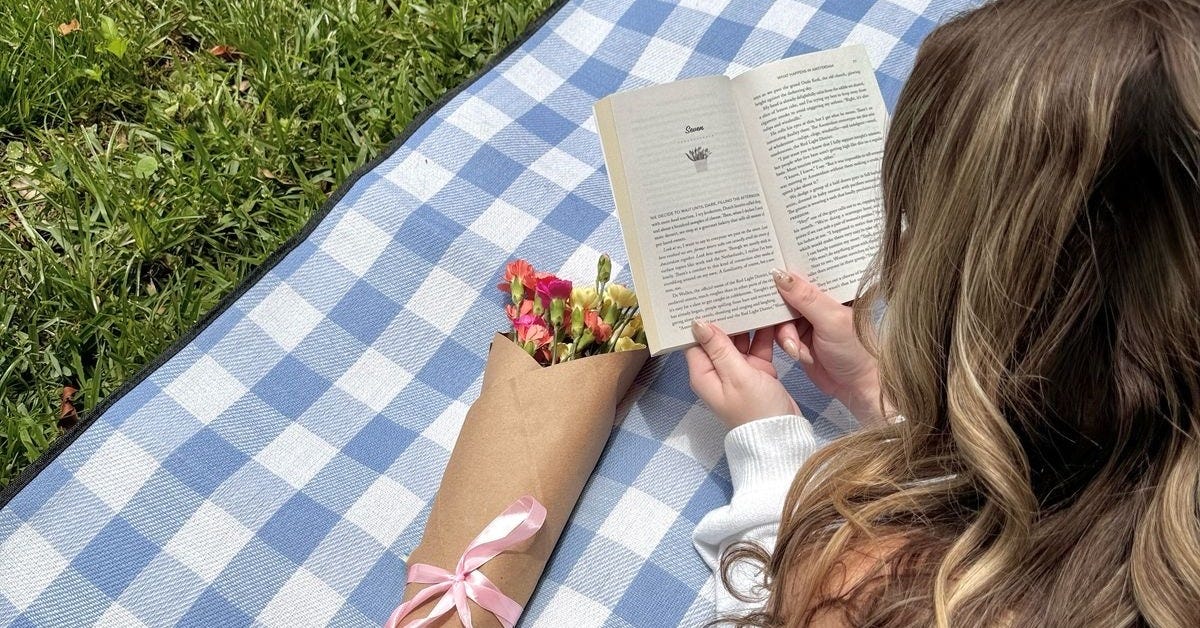 Young woman enjoying a book in a peaceful spring garden, reflecting writer burnout recovery and mental clarity