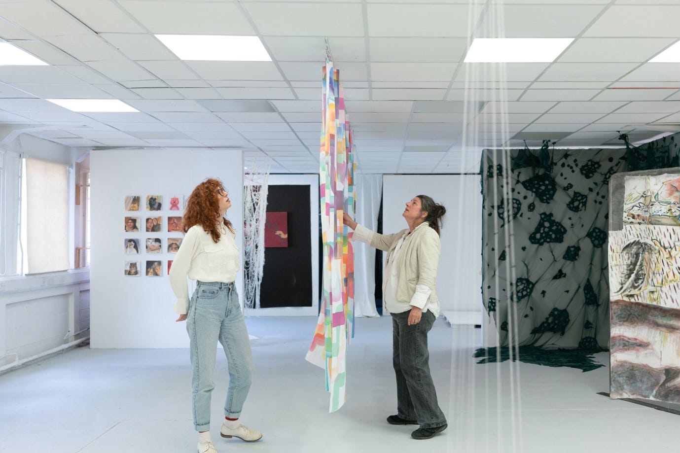 A person looking at a piece of fabric from a ceiling

Description automatically generated