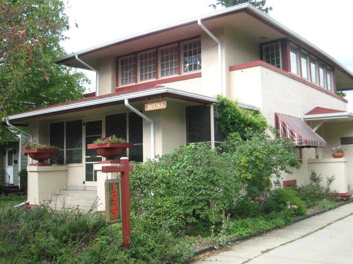 The front of Erasmus Books store, sandy color exterior Prairie-style house with dark red trim.