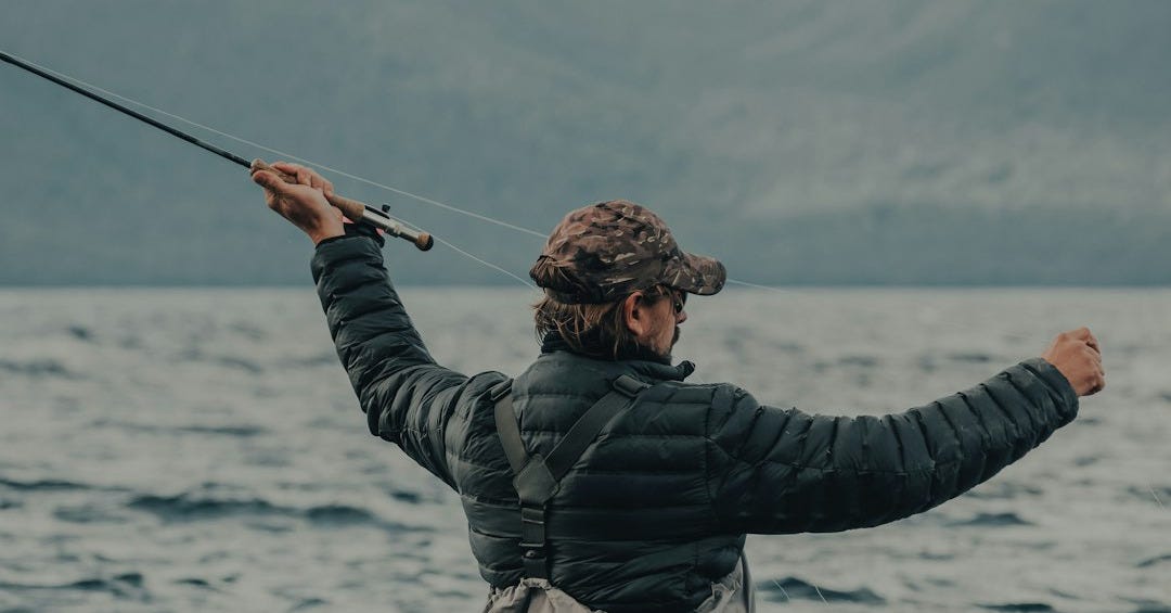 man in black jacket and brown pants holding black fishing rod man in black jacket and brown pants holding black fishing rod