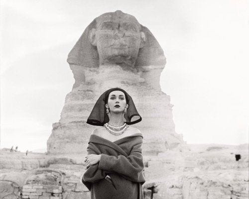 This may contain: an old photo of a woman standing in front of the sphinx