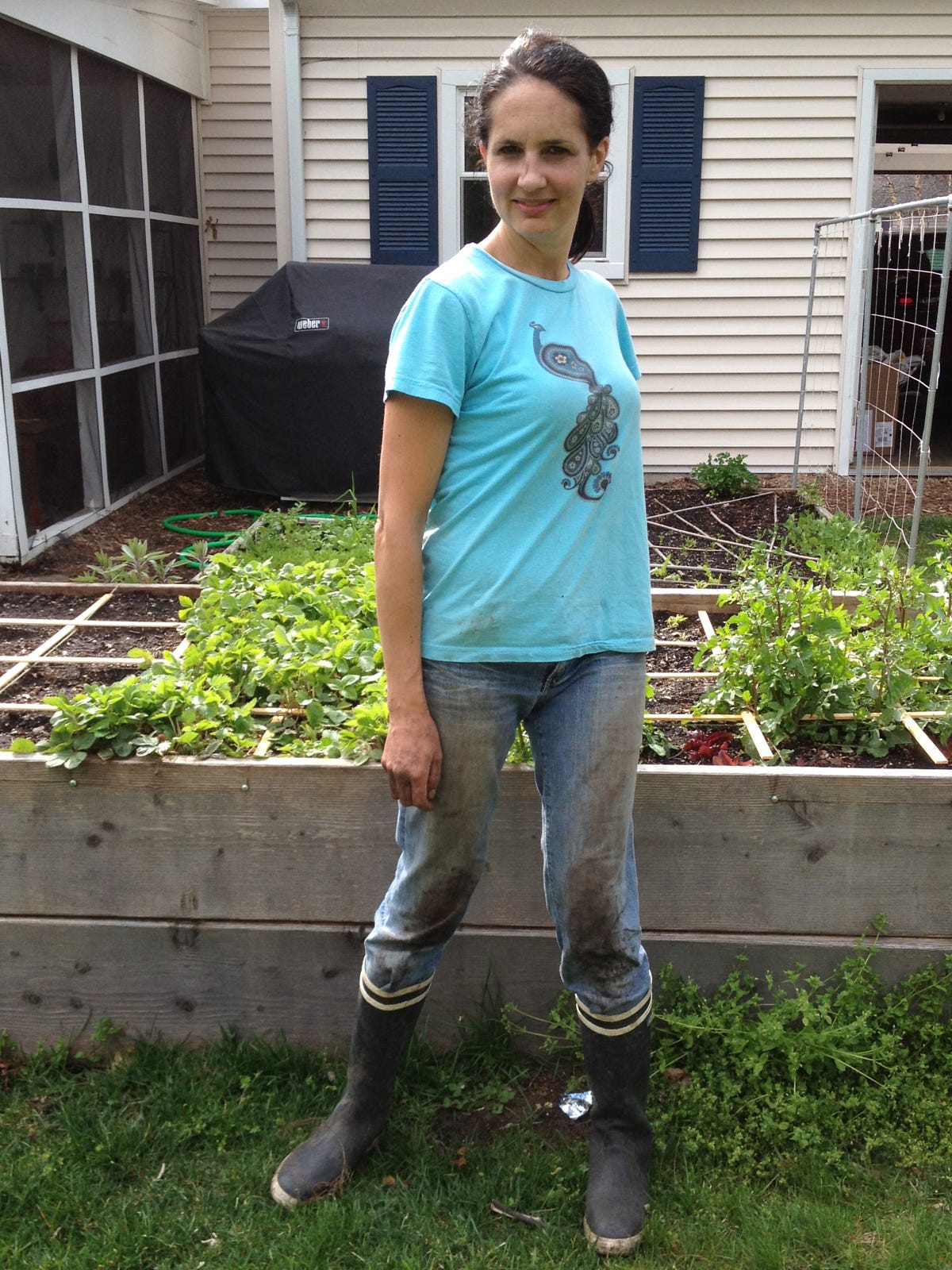 a woman standing in front of a raised bed garden