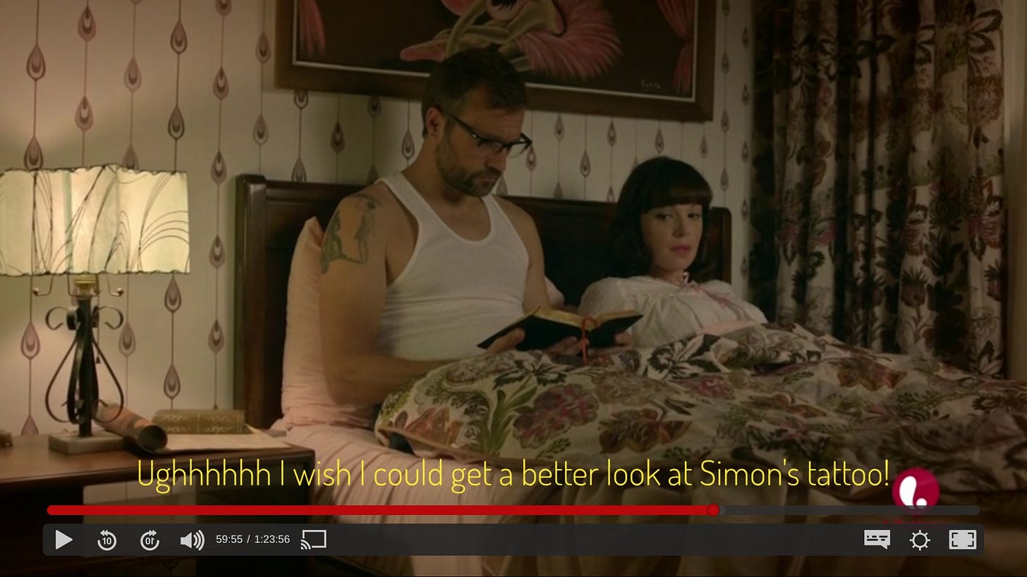 Robin and Simon in bed, under a floral bedspread. Simon has a big tattoo on his bicep but I can't make it out and I'm so mad about it