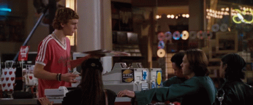 a man in a red shirt is standing in front of a tdk sticker