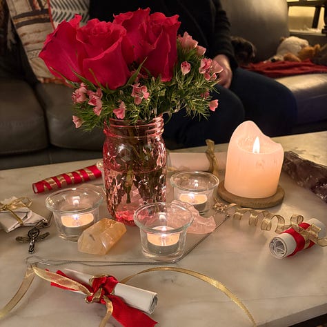 Hot pink roses, scrolls with red and gold ribbon, and crystals for travel ritual
