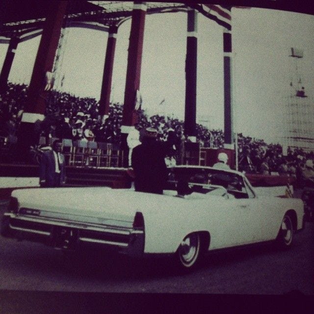 This may contain: an old photo of people standing in front of a white car at a sporting event This may contain: an old photo of people standing in front of a white car at a sporting event