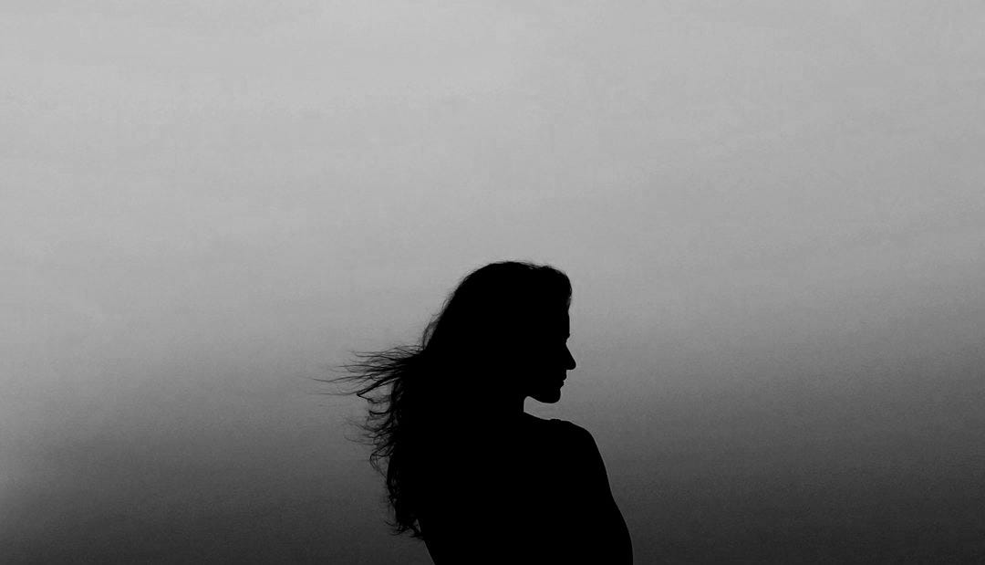 silhouette of woman under orange sky