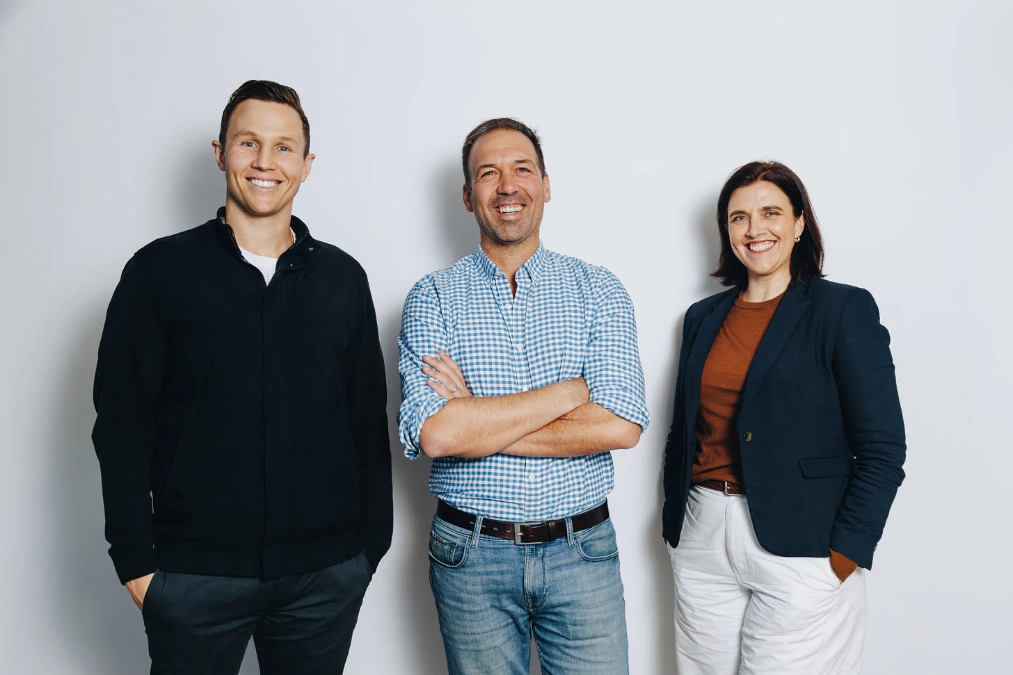 Three members of Jem's leadership team standing together, smiling, against a pale grey studio backdrop.