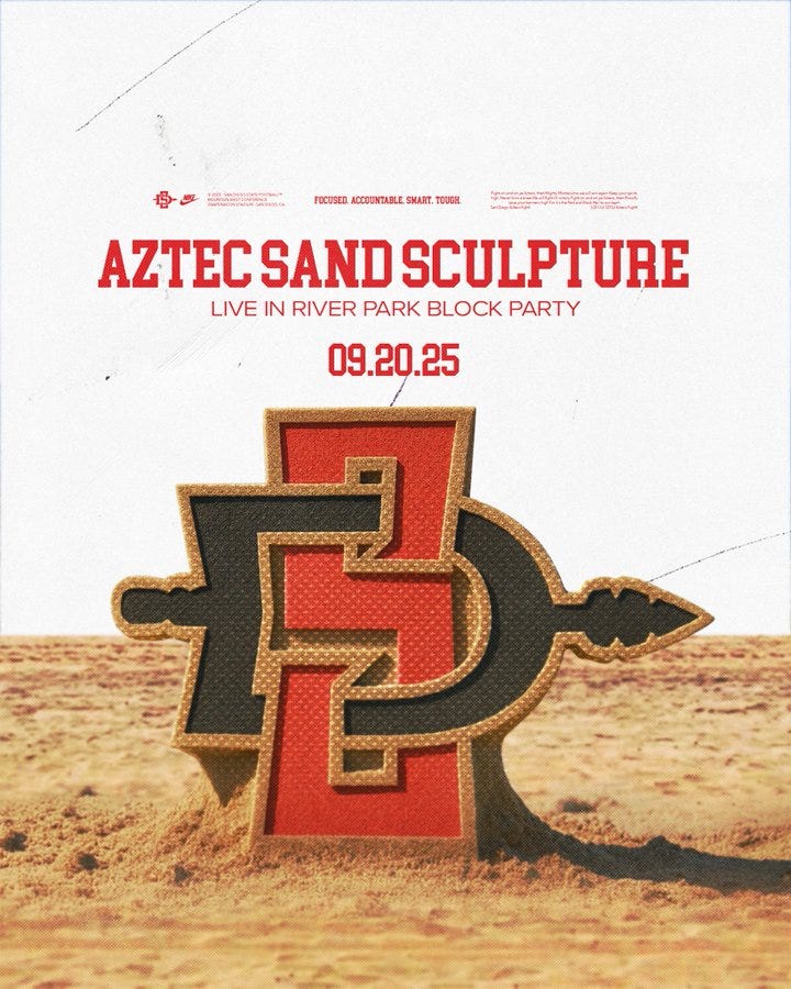 A large sand sculpture of the San Diego State Aztec logo, featuring a red and black design with a stylized letter "A" and a spear. The sculpture is set in a sandy desert-like environment. Text overlay reads "AZTEC SAND SCULPTURE LIVE IN RIVER PARK BLOCK PARTY 09.20.25" in red and white.
