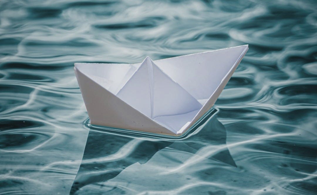 white paper boat on water white paper boat on water