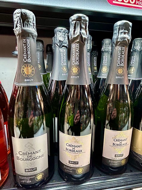 Bottles of different sparkling wines rest on shelves in a French market