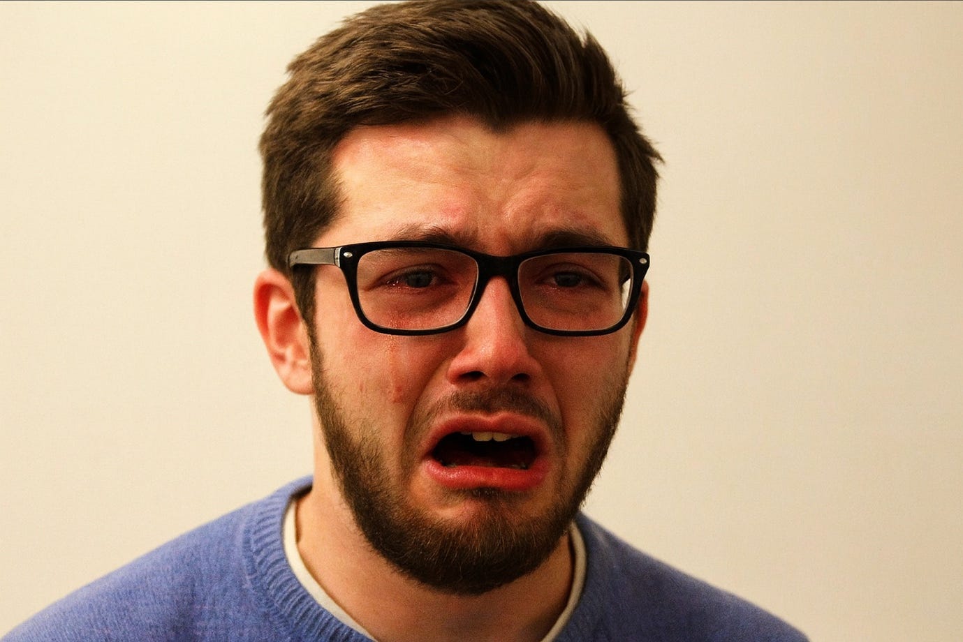 A person with a beard and glasses crying

Description automatically generated