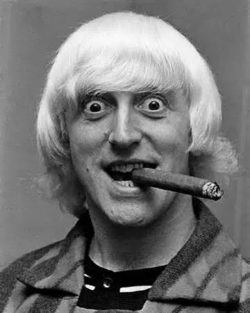 A person with a cigar in his mouth

Description automatically generated