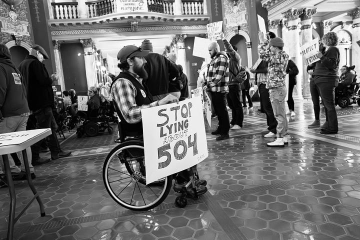 A gallery of black and white photos of a rally in the rotunda of Montana's state capitol. people are holding signs in support of disability rights, there is a podium with legislators speaking, people with a virety of physical disabilities are throughout the crowd.