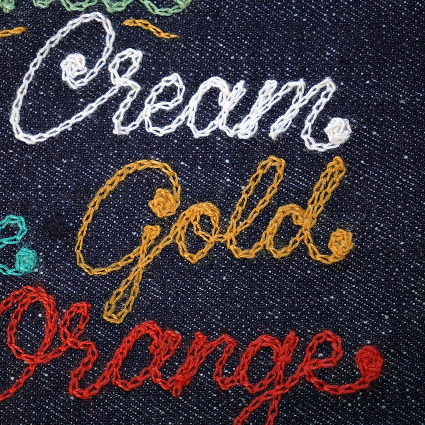 Cream, Gold & Orange written in chainstitch on denim fabric