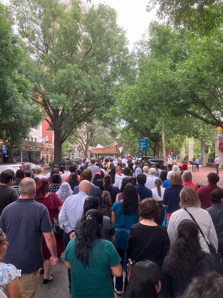 Backs of heads of people of all description walking behind the canopy over the Blessed Sacrament Backs of heads of people of all description walking behind the canopy over the Blessed Sacrament