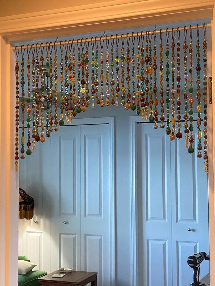 This may contain: an open door with beads hanging from it's side and a table in front